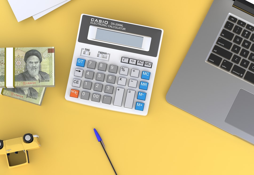 a-calculator-sitting-on-top-of-a-desk-next-to-a-laptop-3hgqb3xhfba